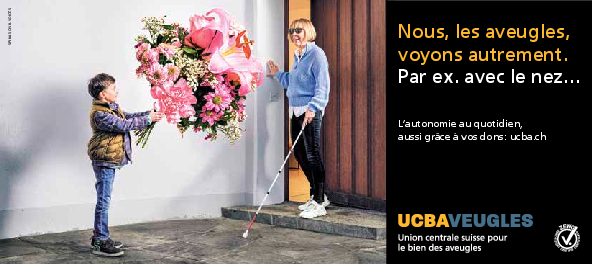 Une femme munie d'une canne blanche se voit remettre un énorme bouquet de fleurs par son petit-fils devant la porte d'entrée.